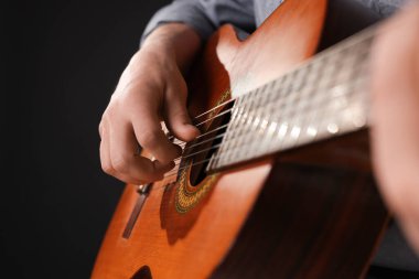 Siyah arka planda gitar çalan adam, ele odaklan.
