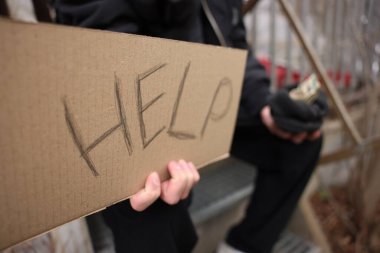 Evsiz adam kelime işareti tutuyor Yardım ve para açık havada, seçici odaklanma