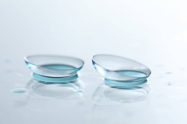 Kontakt lensler ve su damlaları beyaz ayna yüzeyine düşer. Yakın plan.