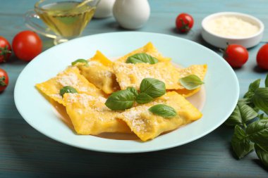 Açık mavi ahşap masada servis edilen peynirli ve fesleğenli lezzetli ravioli.