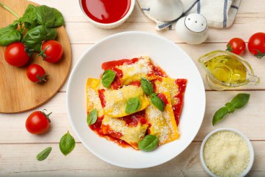 Domates soslu nefis ravioli, parmesan peyniri ve fesleğen beyaz ahşap masada, düz yatıyordu.