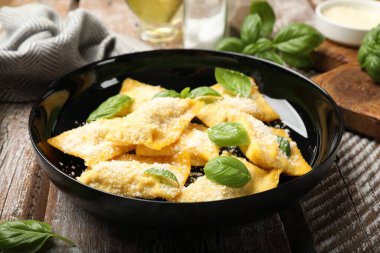 Ahşap masada parmesan peynirli ve fesleğenli lezzetli ravioli, yakın plan.