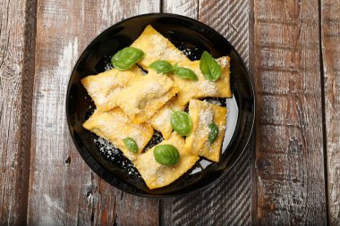 Ahşap masada parmesan peynirli ve fesleğenli lezzetli ravioli.