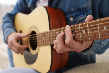 Sandalyede gitar çalan adam, yakın plan.