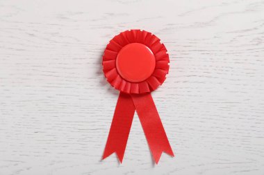 Beyaz ahşap masada kırmızı ödüllü kurdele.