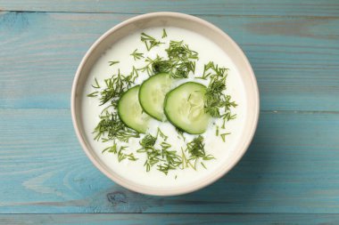 Tabakta salatalık çorbası, açık mavi ahşap masa, üst manzara.