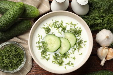 Lezzetli salatalık çorbası kasede ve ahşap masada malzemeler.