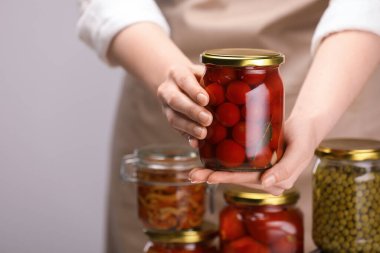 Açık gri arka planda farklı turşulu ürünleri olan bir kadın, yakın plan.