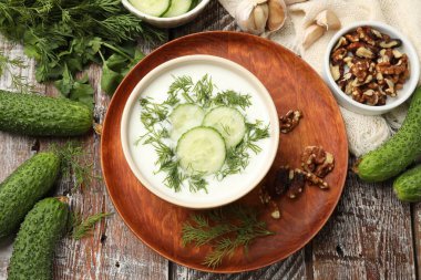 Ahşap masada dereotlu ve fındıklı lezzetli salatalık çorbası.