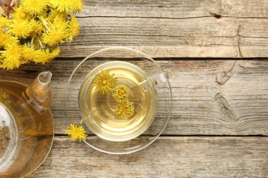 Tazeleyici karahindiba çayı ve çiçekler ahşap masada, düz yatıyordu.