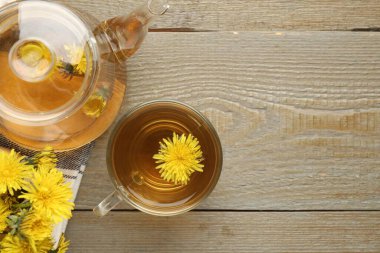 Tahta masada karahindiba çayı ve çiçekler serinletiyor. Metin için boşluk