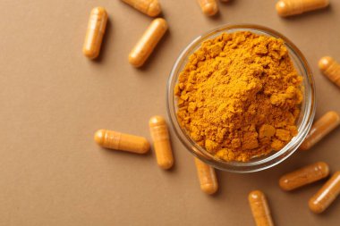 Zerdeçal kapsülleri ve bej arka planda toz, düz bir zemin. Metin için boşluk