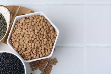 Beyaz fayanslı masa üzerinde farklı mercimek türleri, üst görünüm. Metin için boşluk