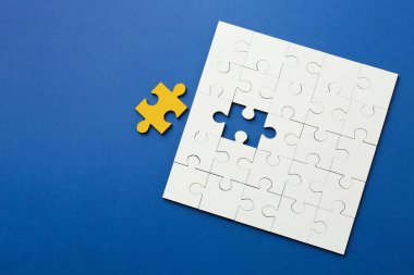 Farklı, eşsiz, özel. Mavi arka planda sarı parçalı beyaz yapboz, üst manzara. Metin için boşluk