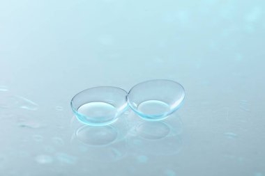 Renkli ayna yüzeyine kontak lens ve su damlaları, yakın plan.