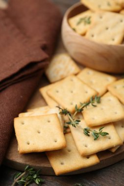 Tahta masanın üzerinde kekik olan lezzetli tuzlu krakerler, yakın plan.