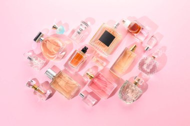 Pembe arka planda çeşitli parfüm şişeleri, düzlük
