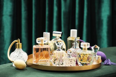 Deniz mavisi perdelerin yanındaki yeşil puf üzerinde farklı lüks parfümler.