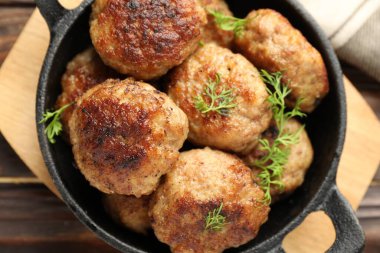 Lezzetli köfteler ve tavadaki dereotlar ahşap masada, üst tarafta.