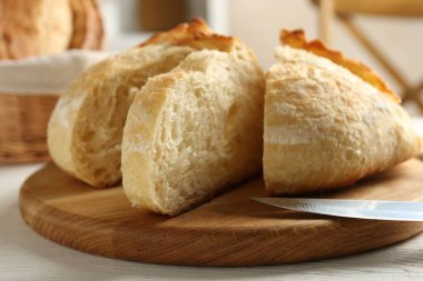 Taze pişmiş ekmek ve bıçağı beyaz ahşap masada kes, yakın plan.