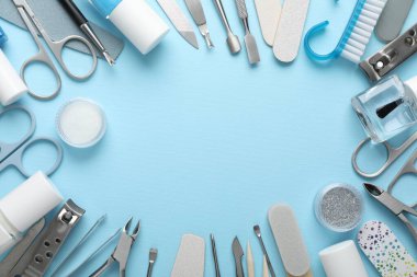 Açık mavi arkaplandaki farklı manikür aletlerinin çerçevesi düz. Metin için boşluk