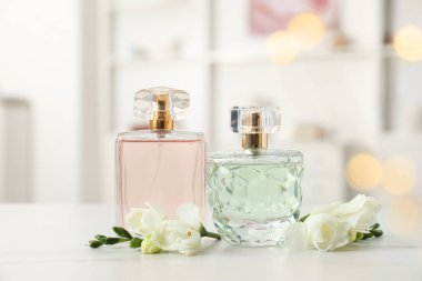 Parfüm şişeleri ve beyaz masada güzel çiçekler.