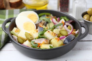 Ringa balıklı lezzetli salata, yumurta ve sebzeler beyaz ahşap masada, yakın plan.