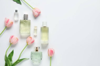 Parfüm şişeleri ve beyaz arka planda güzel çiçekler. Metin için boşluk