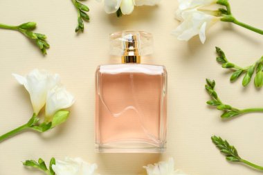 Bir şişe parfüm ve bej arka planda güzel çiçekler.