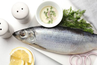 Tuzlu ringa balığı ve baharatlar beyaz masada, düz yerde.