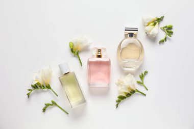 Düz kompozisyon, beyaz arka planda aromatik parfüm şişeleri ve güzel çiçekler vardı.