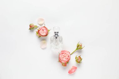 Aromatik parfüm şişeleri ve beyaz arka planda güzel çiçekler.