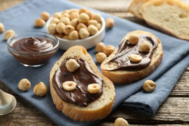 Çikolata sürülmüş ekmek dilimleri ve ahşap masada fındıklar, yakın plan.