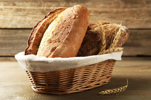 Farklı somunlar taze ekmek ve hasırdan sepetteki çiviler ahşap masada, yakın plan