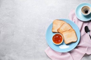 Lezzetli tost ekmeği, reçel ve kahve dilimleri gri desenli masada, düz yerde. Metin için boşluk