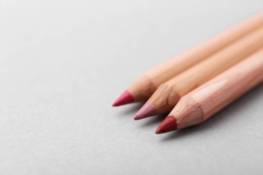 Açık gri arka planda pek çok farklı dudak kalemi, yakın plan. Metin için boşluk