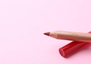 Açık pembe arka planda güzel bir dudak kalemi, yakın plan. Metin için boşluk