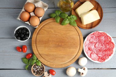 Pizza yapıyorum. Gri ahşap masadaki farklı malzemeler. Metin için boşluk