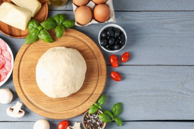 Pizza yapıyorum. Gri ahşap masadaki farklı malzemeler. Metin için boşluk