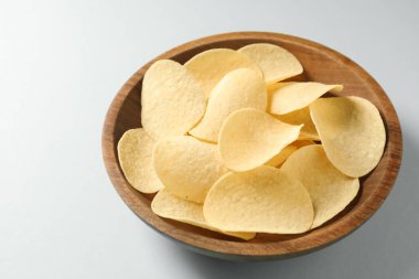 Açık mavi arka planda, kasede patates cipsi, yakın plan.