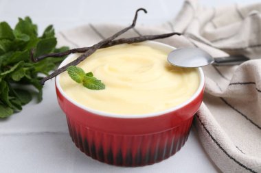 Lezzetli vanilyalı puding, nane ve kapsüller beyaz fayanslı masada, yakın plan.