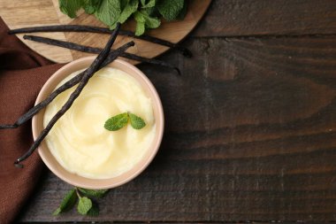 Tasty vanilla pudding, mint and pods on wooden table, flat lay. Space for text