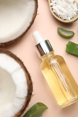 Saç tedavisi. Kozmetik ürünler, hindistan cevizi, tereyağı ve aloe yaprakları bej arka planda, düz konum
