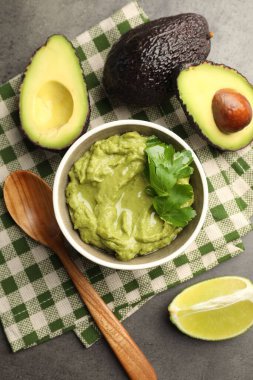 Lezzetli avokado sosu, maydanoz ve meyveler gri masada, düz yerde.