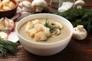 Lezzetli mantar kremalı çorba, kızarmış ekmek, dereotu ve ahşap masa malzemeleri, yakın plan.