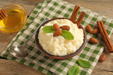 Tahta masada servis edilen bademli, nane ve tarçınlı lezzetli sütlaç, yakın plan.