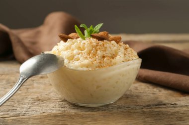 Tarçınlı lezzetli sütlaç, badem ve nane, ahşap masada servis edilir, yakın plan.