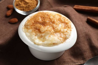 Tabakta tarçınlı, masada bademli lezzetli sütlaç, yakın plan.