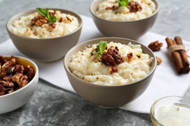 Cevizli, tarçınlı, nane ve ballı lezzetli sütlaç. Gri masada, yakın plan.