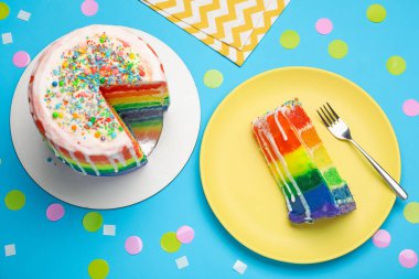 Açık mavi masada konfetiyle servis edilen nefis gökkuşağı pastası.